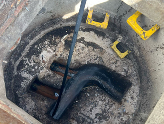 Manhole chamber debris and pipework exposed prior to cleaning and clearance.