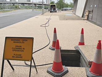 Emergency manhole drain cleaning underway with clear safety signage in place.
