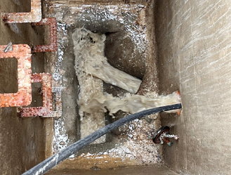 High-pressure water jetting inside a manhole chamber to remove blockages.