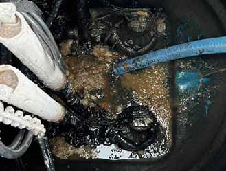 Jet and Drain vacuum tanker using a suction hose to pump waste from a sewage pump station tank during servicing.