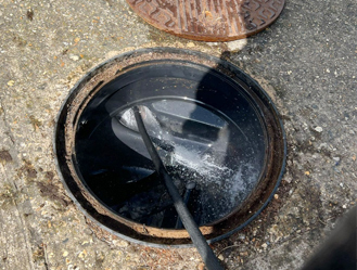 High-pressure water jetting inside a manhole chamber to remove blockages.